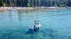 Waterwomen paddle with 2 kids on a crystal clear blue lake with their kids on the front of the paddle board