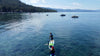 Youth paddle boarder on his Waterkids 9'6 tahoe sup touring sup at lake tahoe.  Boys paddling towards the horizon on a sunny summer day  with boats in the water, mountain, tree and blue sky views