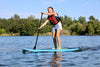 Young girl about 10 or 11 years old paddling from right to left on her light blue color paddle board for kids.  Single paddler on a lake with trees and blue skies.  Lightweight 8ft paddleboard that works properly for kids and is not too big like and adult paddleboard.  Waterkids explorer 8ft kids sup