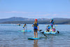 Group of kids and family on paddle boards at lake tahoe with a 12 year old boy in the front on his waterkids 8ft natural hardtop sup looking at the camera.  Beautiful clear water lake with mountains in the background and a family on a 4 person inflatable mantaray paddleboard with a mom and several other children on board.  Everyone in the photo is paddling a waterkids paddle board that are made specifically for kids 