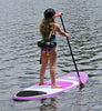 Little girl around 8 or 9 years old on her purple, white and black color waterkids lotus 8ft paddleboard for kids.  She is paddling away with very good paddling technique and is wearing a life jacket and hat while using an adjustable sup paddle specifically sized for children