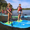 2 girls on their kids stand up paddle boards paddling on a lake with a bridge in the background.  Kids paddle board school in sacramento california for youth paddlers from ages 4 - 14 years old.  The girls are on blue waterkids boards while other children are also paddling behind them having a good time on the water.  They are on the 8ft natural and 8ft explorer kids sup.