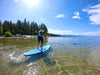 Kid paddleboarding away from the camera on a crystal clear lake in california.  He is paddling a waterkids youth  9'6 surf sup for kids that is also great for getting around on the lake.  Bright blue and green photo with tress and mountains  and clear blue water